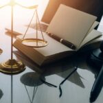 scales of justice, notepad and pen, gavel, and laptop on a lawyer's desk closeup